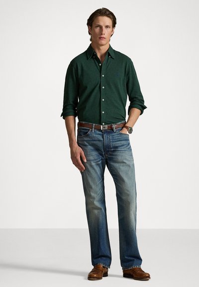 Mørkegrønn knapp-up skjorte, blå slitte jeans, brun skinnbelt, brune sko. Avslappet passform med lange ermer og subtilt merke.