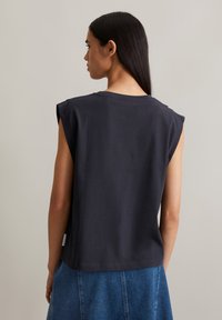 Dark gray sleeveless shirt with a crew neckline, made of cotton. Features rounded shoulder seams and a straight hem.