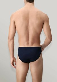 Slip da mare per uomo di colore blu navy con una texture liscia, vita elasticizzata e design minimalista, mostrato da dietro su uno sfondo neutro.