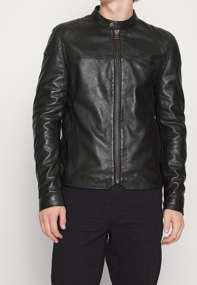 Giacca in pelle nera con colletto alto, chiusura frontale con zip e texture liscia. Presenta dettagli di cucitura e un design aderente.