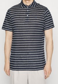 Polo a rayas marino hecho de tejido ligero, con cuello, tapeta de tres botones y un pequeño logotipo bordado en el pecho.