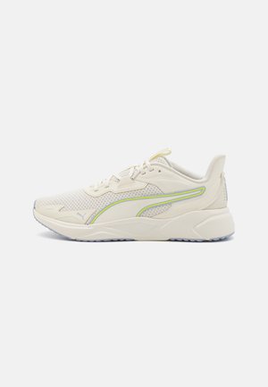 Kremowy sportowy sneaker z siateczkową cholewką, sznurowanym designem i subtelnym żółto-szarym logo Puma z boku i na palcu.