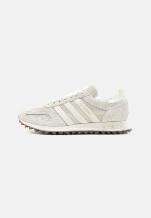 Lysegrå Adidas L.A. Trainer joggesko med overdel i semsket skinn og mesh, hvite striper, brun knottersåle og skolisser, sideprofil.