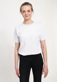 Bíl�á bavlněná tričko s kulatým výstřihem a krátkými rukávy, v kombinaci s černými džíny. Hladká textura a jednoduchý design.