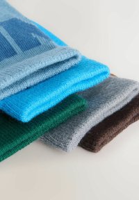 Neli heegeldatud kangatükki, mis on korralikult paigutatud ja millel on sinise, rohelise, halli ja pruuni toonid ning erinevad tekstuurid ja mustrid.