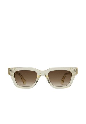 Lunettes de soleil transparentes avec une forme géométrique en œil de chat ; verres dégradés marron ; monture transparente élégante ; accents dorés sur les branches.