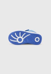 Blå sneakersåle med teksturert gummi, med kontrasterende hvite detaljer og spor for grep. Designet inkluderer et sirkulært element.