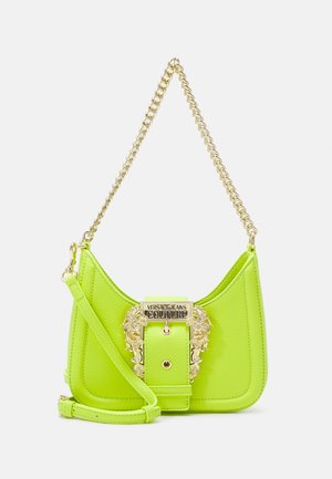 Mała neonowo-zielona skórzana torebka na złotym łańcuszku z ozdobną złotą klamrą z napisem „Versace Jeans Couture” z przodu.