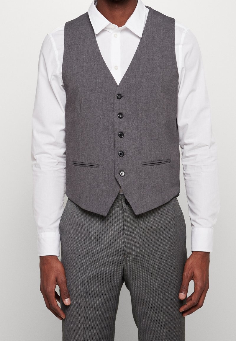 Szary, dopasowany kamizelka o wąskim kroju, z dekoltem w serek, sześcioma guzikami z przodu, dwiema bocznymi kieszeniami oraz gładką teksturą. Połączony z białą koszulą.