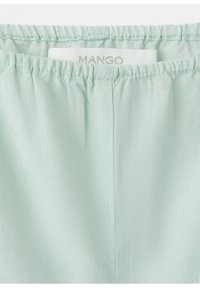 Tissu vert clair avec taille élastique et étiquette de marque "MANGO" visible cousue à l'intérieur.