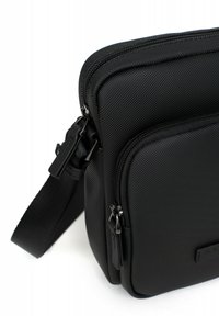 Borsa messenger nera con esterno in nylon testurizzato, scomparti con cerniera doppia e tracolla regolabile. Accenti in metallo nero notevoli.