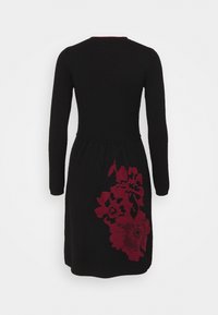 Robe noire à manches longues avec une taille cintrée et un grand motif floral rouge foncé sur le bas du dos du côté droit.