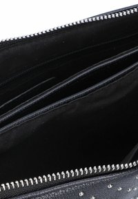 Portafoglio sintetico nero con borchie argentate, chiusura con zip e diversi slot per carte. L'interno presenta una texture liscia e scomparti divisi.