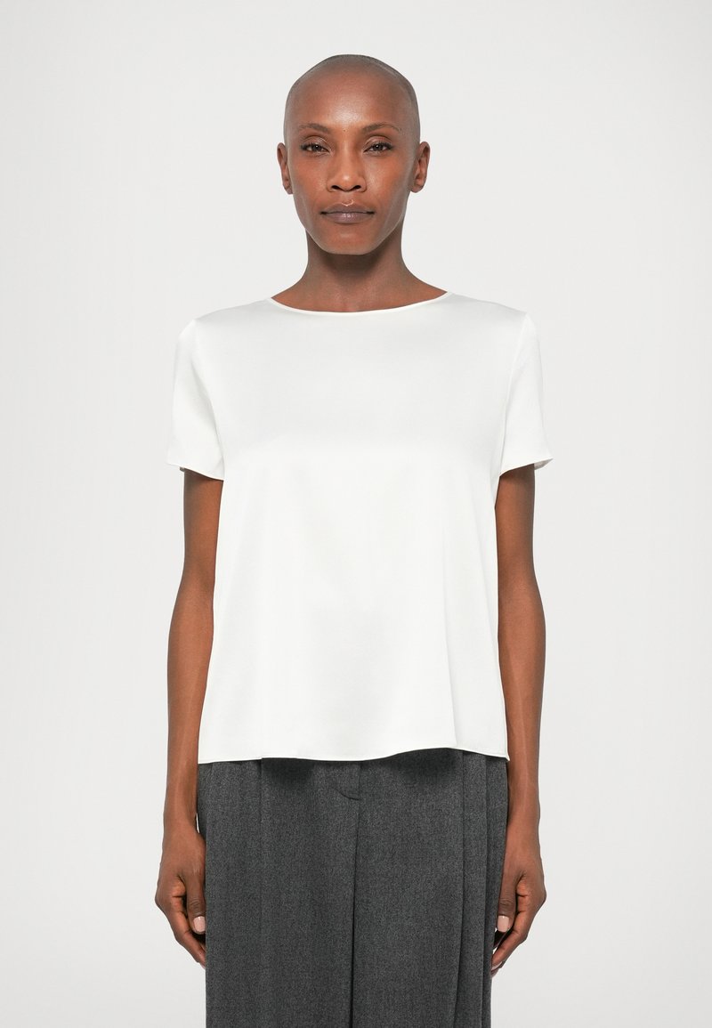 Λευκή κοντομάνικη μπλούζα με στρογγυλή λαιμόκοψη, φτιαγμένη από απαλό ύφασμα. Συνδυασμένη με γκρι παντελόνι με φαρδιά γραμμή που δημιουργεί άνετη εφαρμογή.