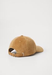 Cappellino da baseball in corduroy color sabbia con fibbia metallica regolabile, visto da dietro su uno sfondo bianco semplice.