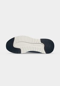 Semelle de chaussure avec motif ondulé, noire à l’avant et au talon, partie centrale blanche avec la marque « Marc O’Polo » en relief au centre.