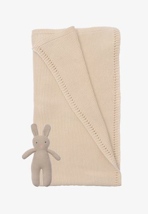 Beige knitted blanket folded with a textured edge, accompanied by a soft, beige rabbit toy with stitched facial features.