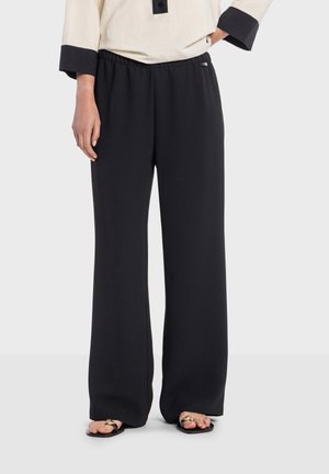 Sorte vidde bukser med elastisk talje, lavet af let stof. Kombineret med sorte sandaler med dekorative metalaccent.