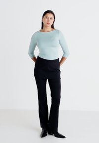 Hele sinine kitsas pika varrukaga topp, mis on koos mustade sirgete pükstega. Tofil on ümar kaelus ja sile tekstuur, samas kui püksid on elegantsed.