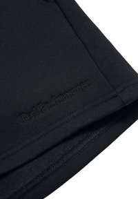 Schwarzer Sportstoff mit glatter Textur und gesteppten Säumen. Verfügt über ein dezentes, eingeprägtes "PeakPerformance"-Logo auf dem Material.