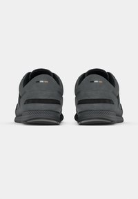 Baskets en daim noir à profil bas, avec des panneaux texturés et une semelle en caoutchouc. Détails remarquables : petits accents de couleur contrastante sur le talon.