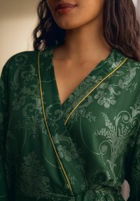 Robe verde con motivo floreale e rifiniture dorate. Realizzata in tessuto liscio, presenta un design avvolgente e una superficie testurizzata con dettagli intricati.