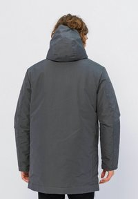 Grijze, geïsoleerde parka met een capuchon. Heeft een soepele textuur en rechte snit. De achterkant toont stikdetails en is iets langer van lengte.