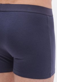 Bóxers ajustados de algodón azul marino con un diseño ceñido, textura suave y una cintura elástica y cómoda. Detalles de costuras visibles en los laterales.