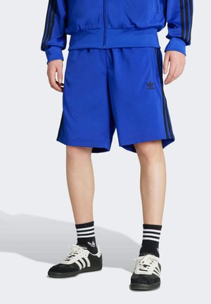 Blue athletic shorts with black side stripes, made of a smooth synthetic material. Features an Adidas logo on the left leg.