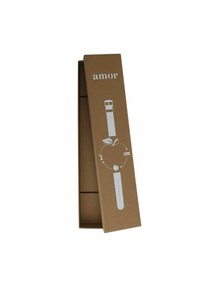Kartonbox mit weißen Grafiken und Text, die ein Uhrenarmband enthält. Das Armband weist ein kreisförmiges Lochmuster und eine Dornschließe auf.