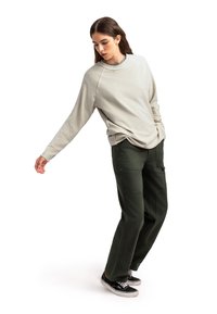 Felpa grigia chiara a maniche lunghe con vestibilità rilassata abbinata a pantaloni cargo verde scuro con molteplici tasche e un tessuto testurizzato.
