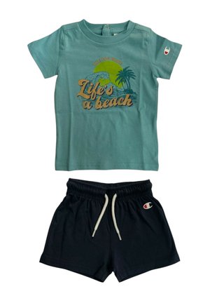 Maglietta blu per bambino piccolo con scritta "Life's a beach" e design a onda, abbinata a pantaloncini con elastico nero in vita e coulisse bianche.
