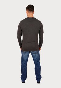 Cămașă lungă, din material cărbune, cu guler rotund, din țesătură texturată, și blugi blue. Cămașa are un design simplu și elegant.