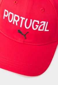 Căciulă roșie de baseball cu broderie "PORTUGAL" în alb și un logo Puma negru. Material texturat cu o margine curbată și detalii de cusătură.