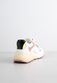 Sneaker med ovandel i mesh i vitt, grå detaljer och en häl i rosa och svart. Har en gul detalj på sidan och en kraftig sula.