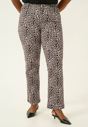 Woman wearing leopard print straight-leg pants with button and zipper closure paired with black pointed-toe slingback heels.