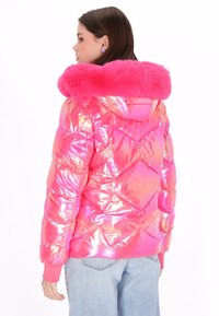 Różowa, błyszcząca kurtka puchowa z puszystym różowym kołnierzem, ozdobiona diamentowym wzorem pikowania i ściągaczami na rękawach, noszona z jasnoniebieskimi dżinsami.