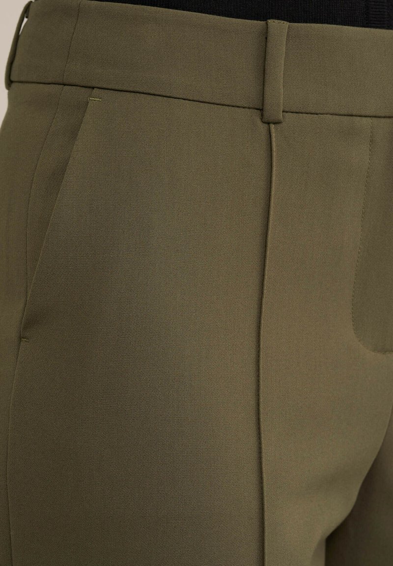 Olijfgroene op maat gemaakte broek met een gladde textuur, voorzien van een rechte voorkant, zijzakken en een subtiele plooi langs iedere pijp.