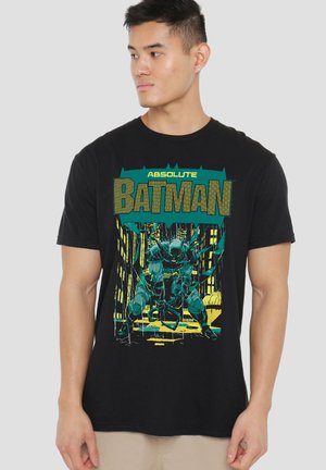 Young man wearing a black t-shirt with a green and yellow Batman graphic and the words "Absolute Batman" on the front.