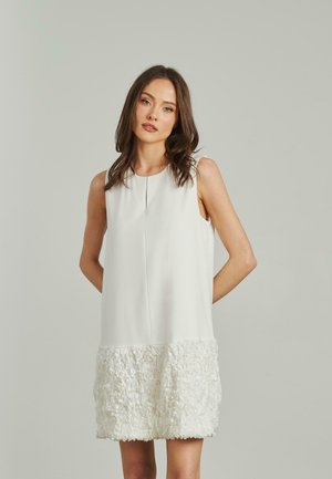 Abito bianco senza maniche con un corpino liscio e un orlo arricciato testurizzato. Realizzato in tessuto leggero con una silhouette moderna.