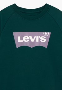 Zelená mikina s fialovou grafikou obsahující bílé logo Levi's, kulatým výstřihem a žebrovanými lemy na rukávech.