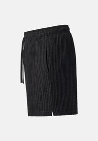 Short noir texturé longueur genou avec taille élastique et poches latérales, montré en angle latéral sur un fond uni.