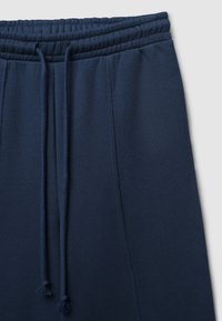 Pantaloni sportivi blu navy con vita elastica, coulisse regolabile, superficie liscia e gambe affusolate con cuciture laterali.