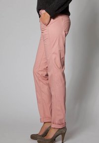 Ljusrosa bomullschinos med framfickor och uppvikta ärmar, tillsammans med grå högklackade skor. Slät struktur och skräddarsydd passform.