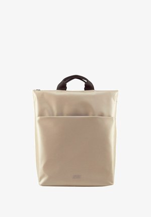 Sac à dos beige avec poignées noires, fabriqué en matériau texturé ; il dispose d'une poche frontale et d'une fermeture éclair. Forme carrée, design minimaliste.