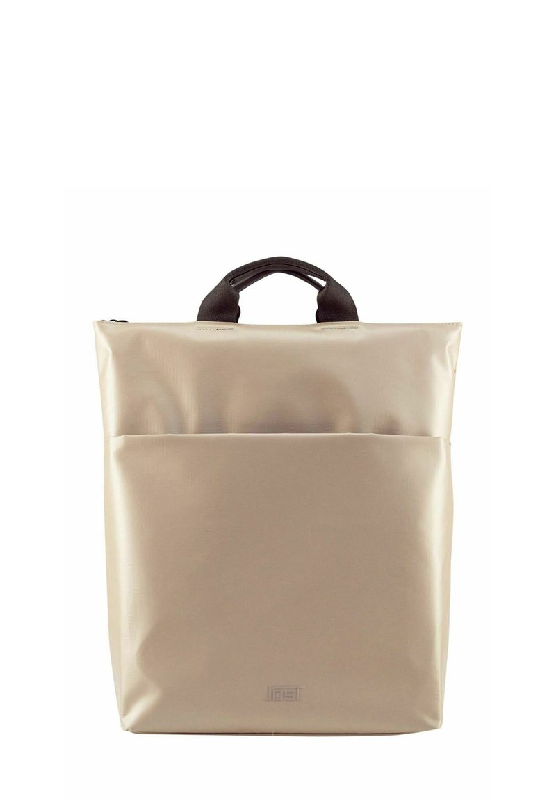 Sac à dos beige avec poignées noires, fabriqué en matériau texturé ; il dispose d'une poche frontale et d'une fermeture éclair. Forme carrée, design minimaliste.