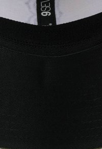 Schwarze Baumwollmütze mit einer passgenauen Form, die eine einfarbige Textur und ein gesticktes Band aufweist. Das Etikett im Inneren trägt die Aufschrift "9SEVEN".