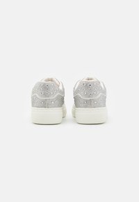 Sneakers argento con accenti luccicanti, suole in gomma bianche, forma arrotondata e superfici testurizzate; presenta un design decorativo a onde.