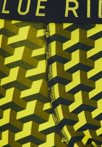 Spodenki kompresyjne z geometrycznym wzorem w kolorze żółtym i ciemnozielonym, z czarną gumką w pasie z napisem "BLUE RIDE". Teksturowany i elastyczny materiał.