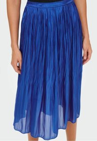 Kuningan midi pleat berwarna biru royal terbuat dari kain ringan dengan tekstur mengkilap, dilengkapi dengan pinggang elastis untuk kenyamanan.